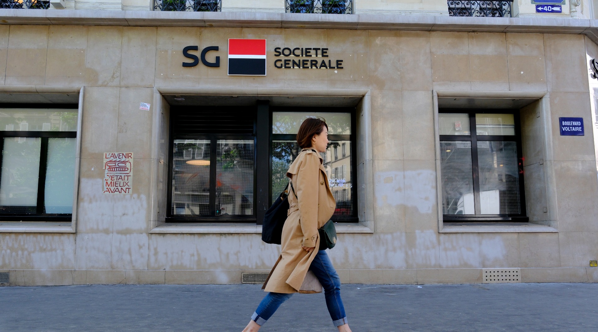 A woman walking in front of a Societe Generale branch