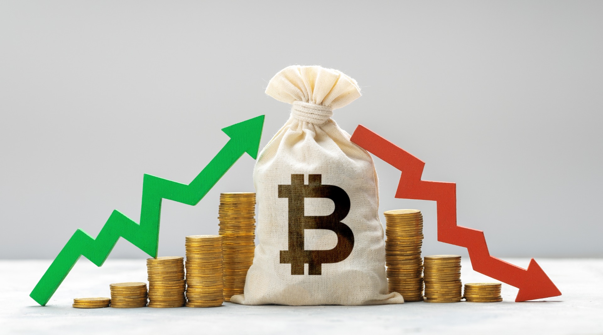 Bitcoin bag staying in the center of stash of coins and two arrows: green up and red down
