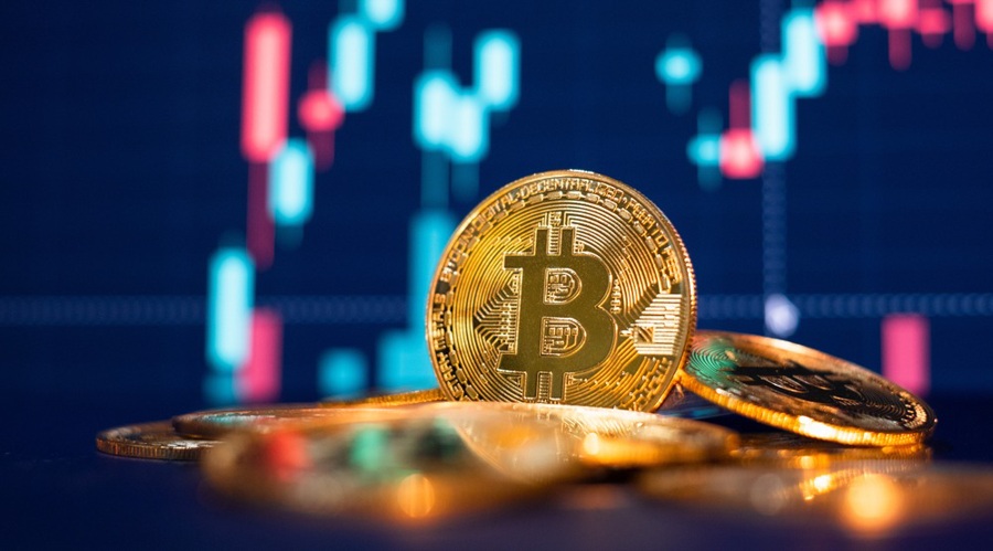 The picture of Bitcoin token in the forefront with a candle chart in the background.