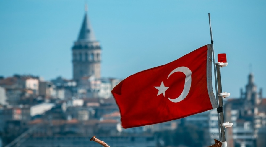 Galata Tower and Turkish flag waving on the boat in the background.