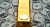 Bitcoin on top of the gold bar which lays on the stack of us dollars