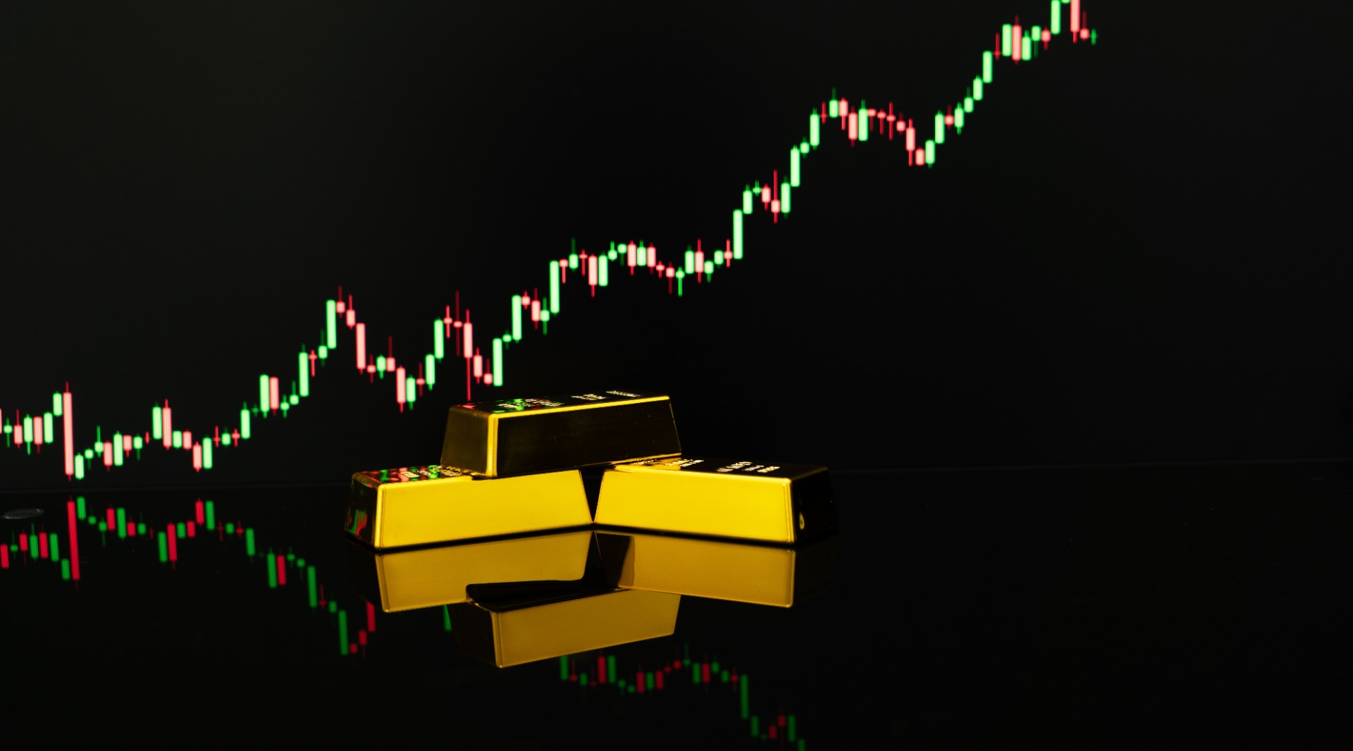 Gold bars laying one on each other with gold price chart behind, dark background